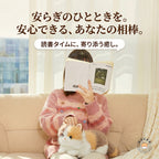ソファで膝に乗せた三毛猫のぬいぐるみに優しく手を添える読書タイム