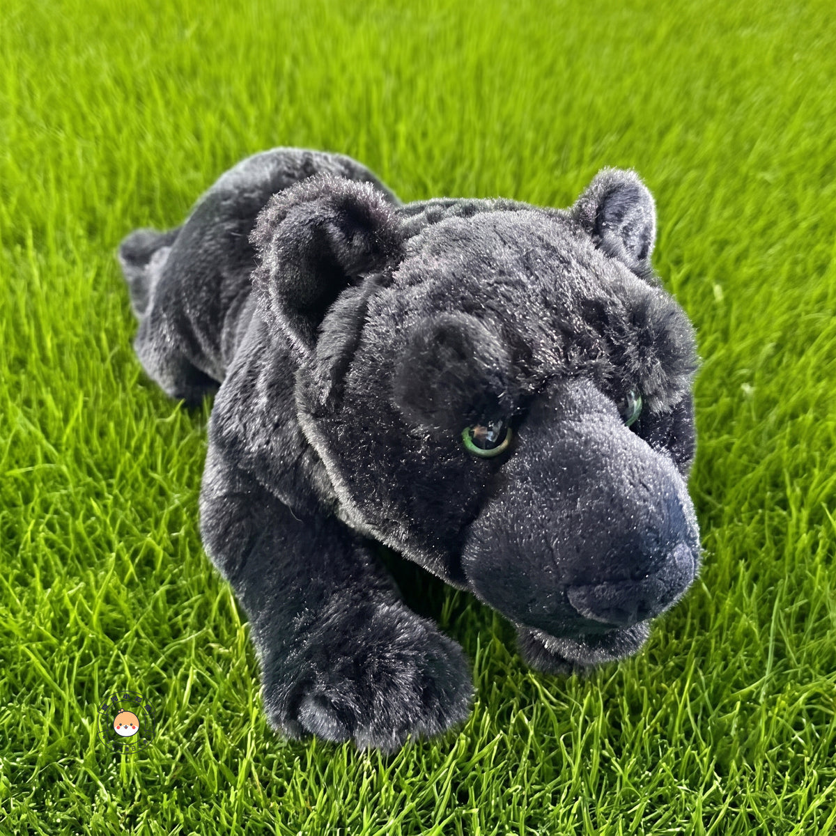 芝生の上で前足を伸ばして見上げてくるリアルなクロヒョウぬいぐるみ。お外でもお家でも寄り添う小さな相棒