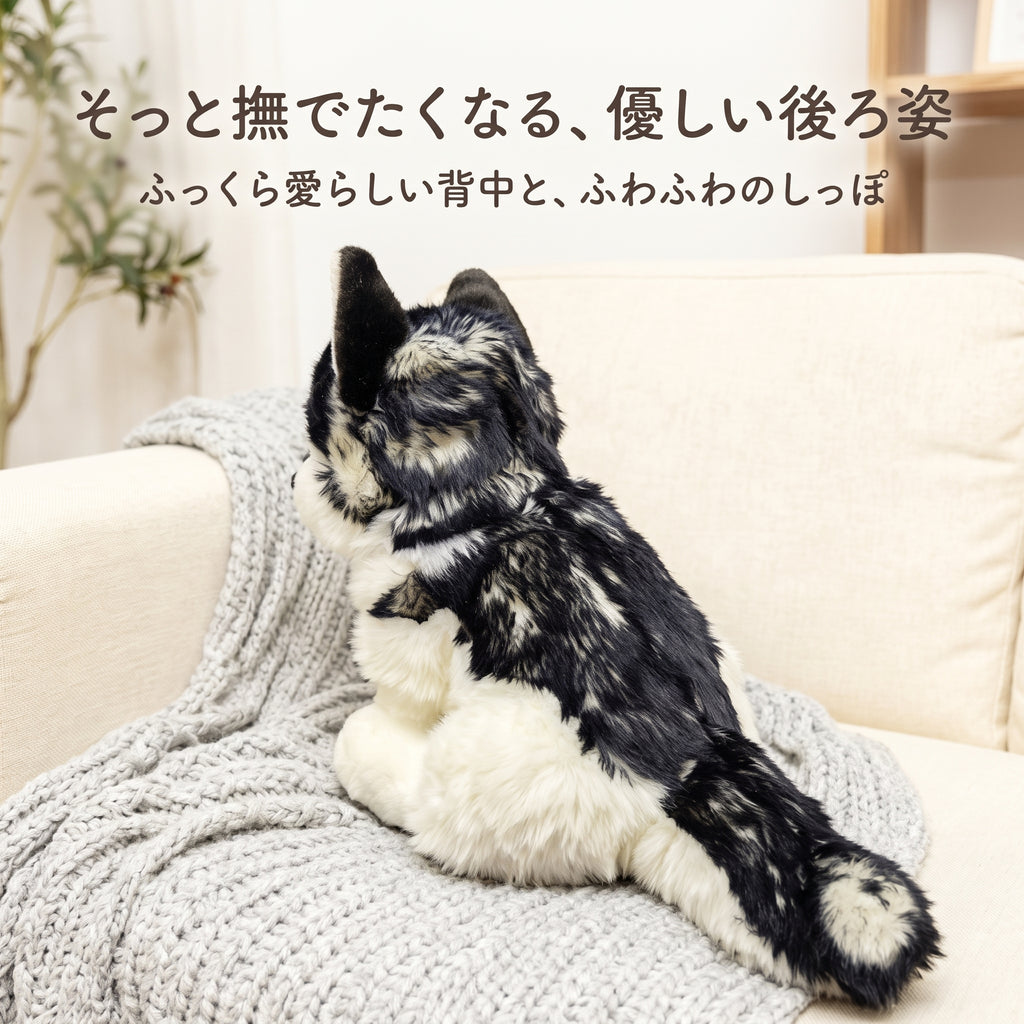ソファの背もたれに寄り添うハスキーぬいぐるみの後ろ姿。ふっくらと丸みのある背中ともふもふの愛らしいしっぽ