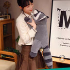 大きいアライグマのぬいぐるみを抱き枕のように抱えるイメージ