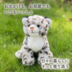 緑の芝生の上で前足を揃えてお座りするリアルユキヒョウぬいぐるみ。日々の暮らしにそっと寄り添う小さな相棒