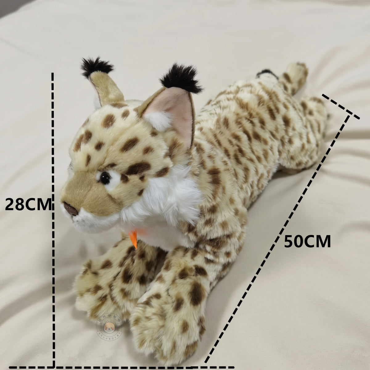 ベッドの上に寝そべるオオヤマネコぬいぐるみのサイズ感。全長約50cm・全高約28cmのボリューミーな存在感
