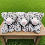 ウッドベンチに仲良く並んで寝そべる3匹のユキヒョウぬいぐるみ。まるで本物の動物園のような愛らしい空間演出